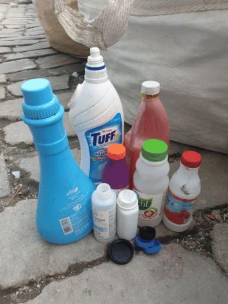 A group of collected HDPE bottles and containers standing on paving