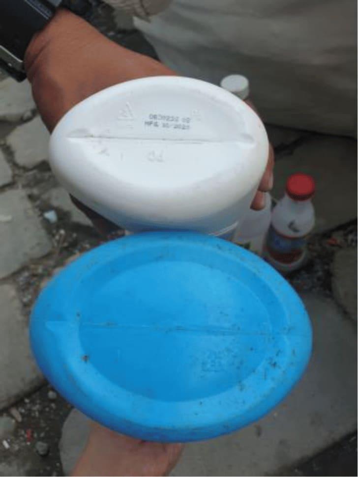 A hand holding two plastic lids up to check the resin code moulded into them