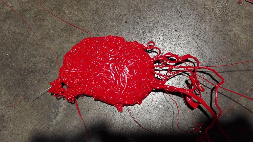 A tangle of red melted plastic that has cooled on a concrete floor