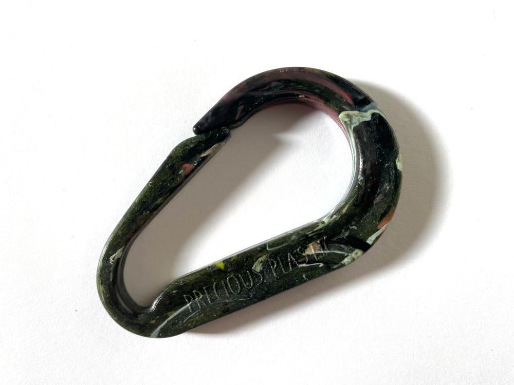 A dark green marbled carabiner moulded from recycled plastic